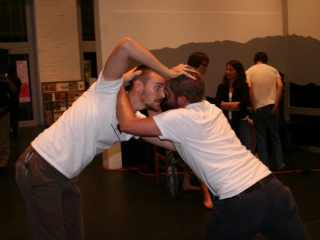 Documentation of a performance featuring a team of &ldquo;coal miners&rdquo; and a team of &ldquo;astronomers,&rdquo; in which members of opposing teams wrestle with their eyes physically pressed against each other