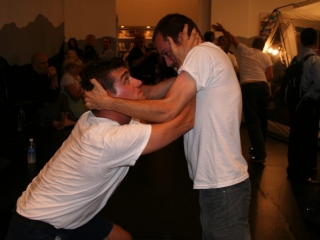 Documentation of a performance featuring a team of &ldquo;coal miners&rdquo; and a team of &ldquo;astronomers,&rdquo; in which members of opposing teams wrestle with their eyes physically pressed against each other