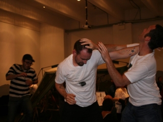 Documentation of a performance featuring a team of &ldquo;coal miners&rdquo; and a team of &ldquo;astronomers,&rdquo; in which members of opposing teams wrestle with their eyes physically pressed against each other