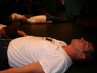 Documentation of a performance featuring a team of &ldquo;coal miners&rdquo; and a team of &ldquo;astronomers,&rdquo; in which members of opposing teams wrestle with their eyes physically pressed against each other