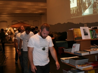 Documentation of a performance featuring a team of &ldquo;coal miners&rdquo; and a team of &ldquo;astronomers,&rdquo; in which members of opposing teams wrestle with their eyes physically pressed against each other