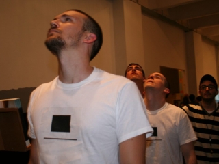 Documentation of a performance featuring a team of &ldquo;coal miners&rdquo; and a team of &ldquo;astronomers,&rdquo; in which members of opposing teams wrestle with their eyes physically pressed against each other